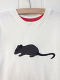 Close up of natural white organic cotton, short-sleeved t-shirt on a hanger with a hand applique mouse on the front. The mouse is made of fine stripe grey cotton melange, with black eye, ears and tail. The inside neck has a stylish red trim. Designed and hand made in the Isabee London studio. Available in two sizes for kids (2-5 years of age). Baby Mouse is available for age 3-24 months.