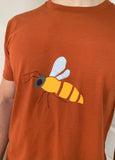 Burnt orange short-sleeved t-shirt for adults with bee applique on the front. Yellow body, white wings, grey head and black eye, antennae and legs. isabee