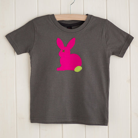 Dark grey children's t-shirt featuring a fuchsia pink appliqued rabbit with a leaf green tail. T-shirt is displayed on a hanger in front of a white panelled background. - isabee.co.uk