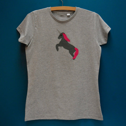 Grey melange fitted tshirt. Slim fit or women's fit with cap sleeves. T-shirt features a dark grey Appliquéd Unicorn design with a reflective horn and a pink mane and tail. Unicorn is rearing on its hind legs. T-shirt is on a hanger in front of a teal background. - isabee.co.uk